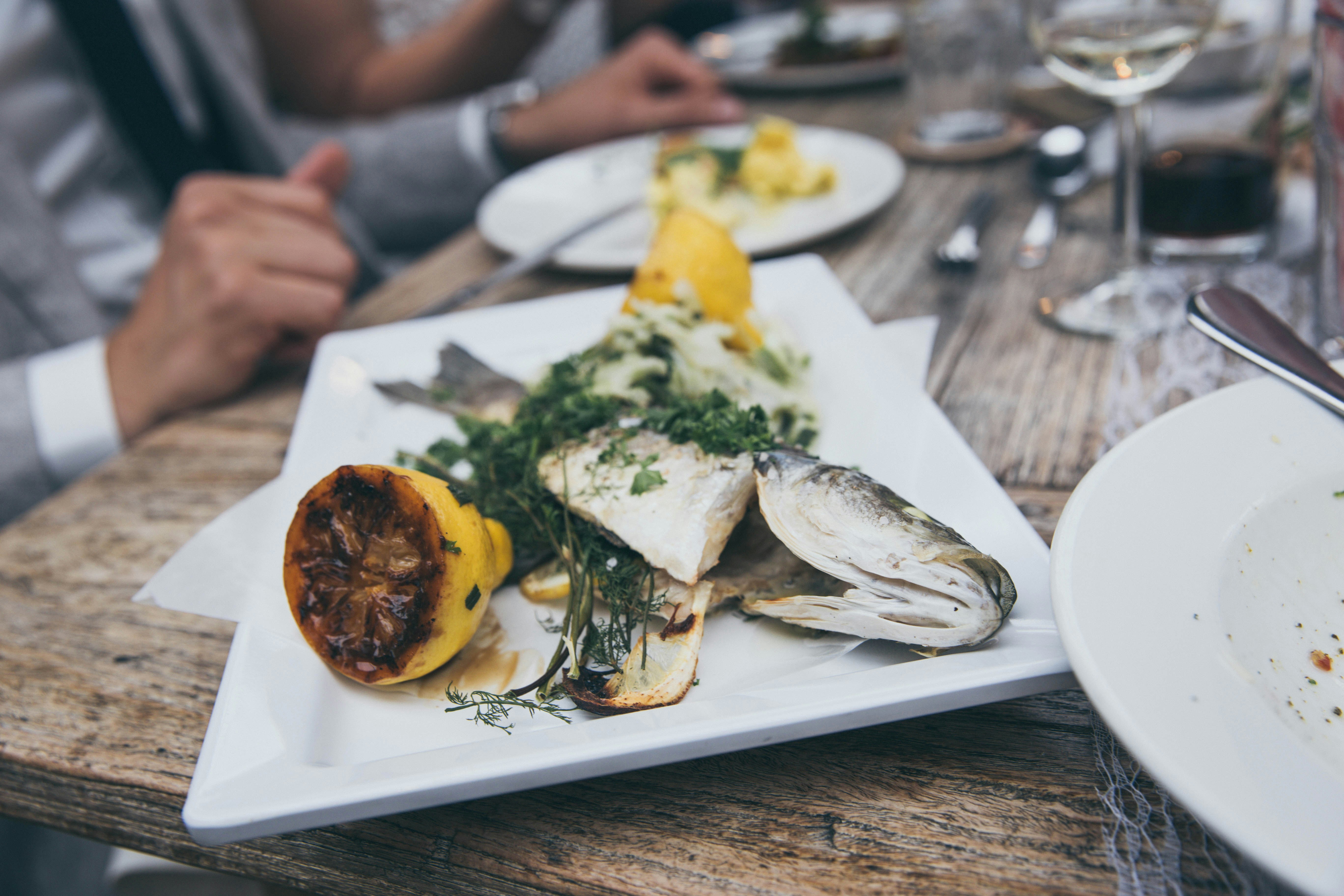Et glas frisk hvidvin ved siden af en tallerken med grillet fisk og skaldyr