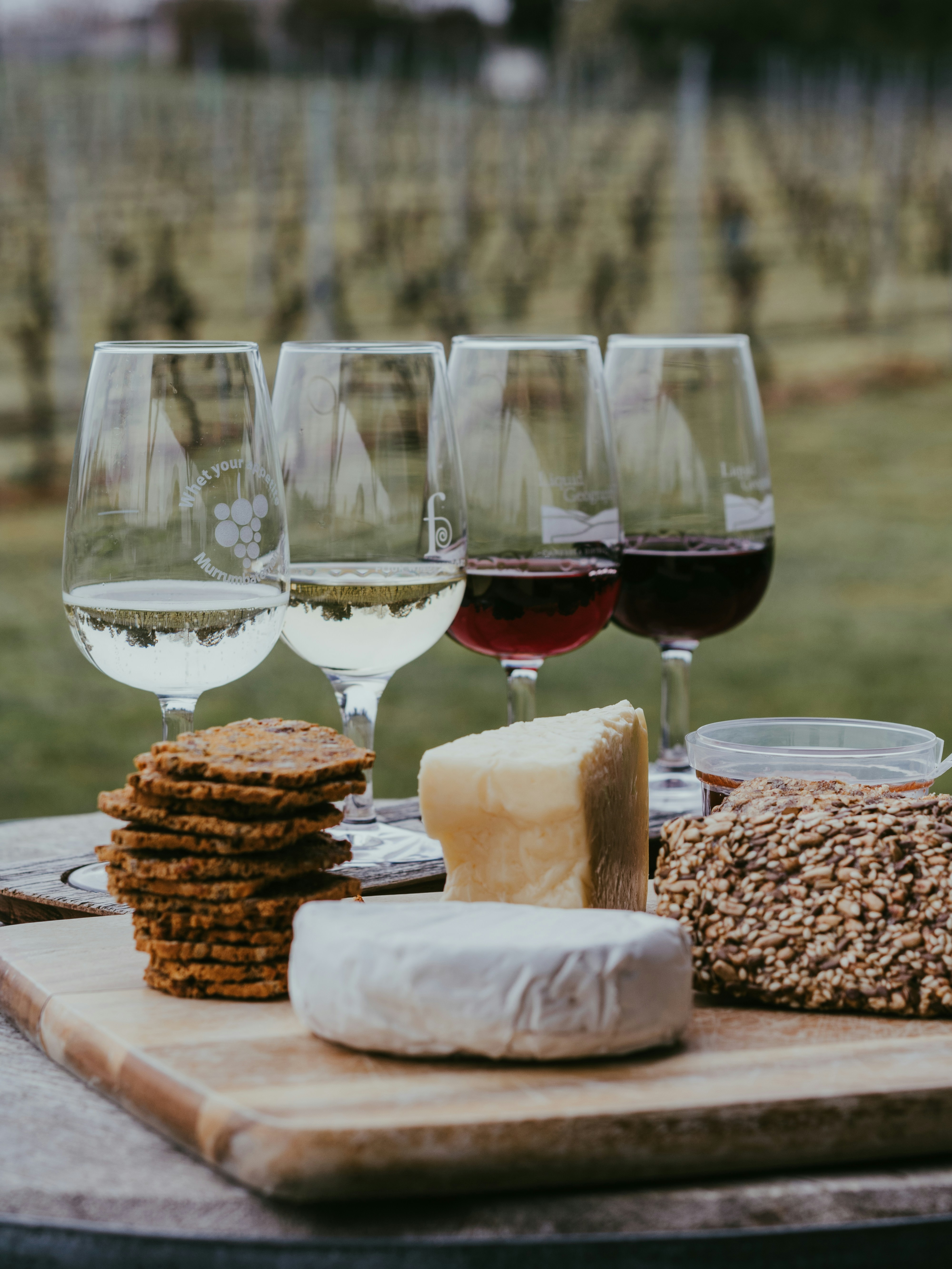 Ostebord med forskellige ostetyper, druer og et glas vin